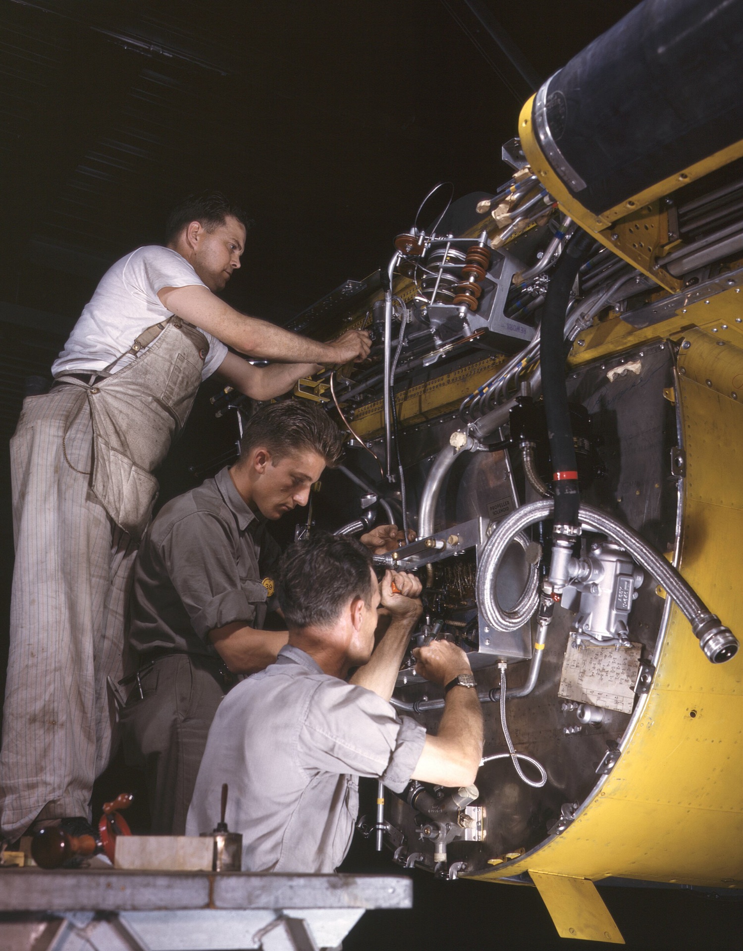 Technicians inspecting wiring and piping inside an aircraft