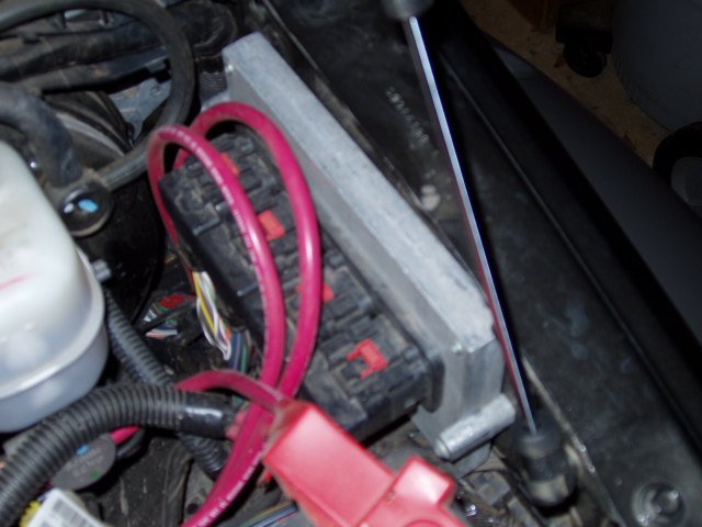 An installed engine-control module shows the crowded routing around powertrain electronics.