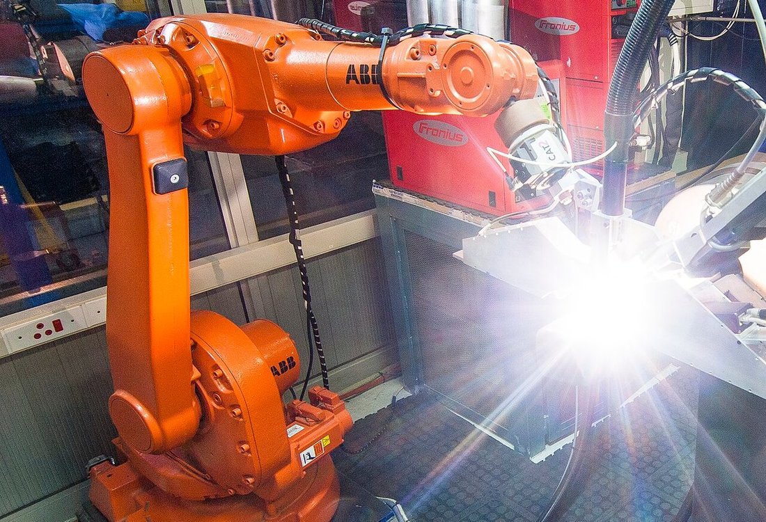 Robotic welding illustrates heat, motion and electromagnetic exposure around equipment wiring.