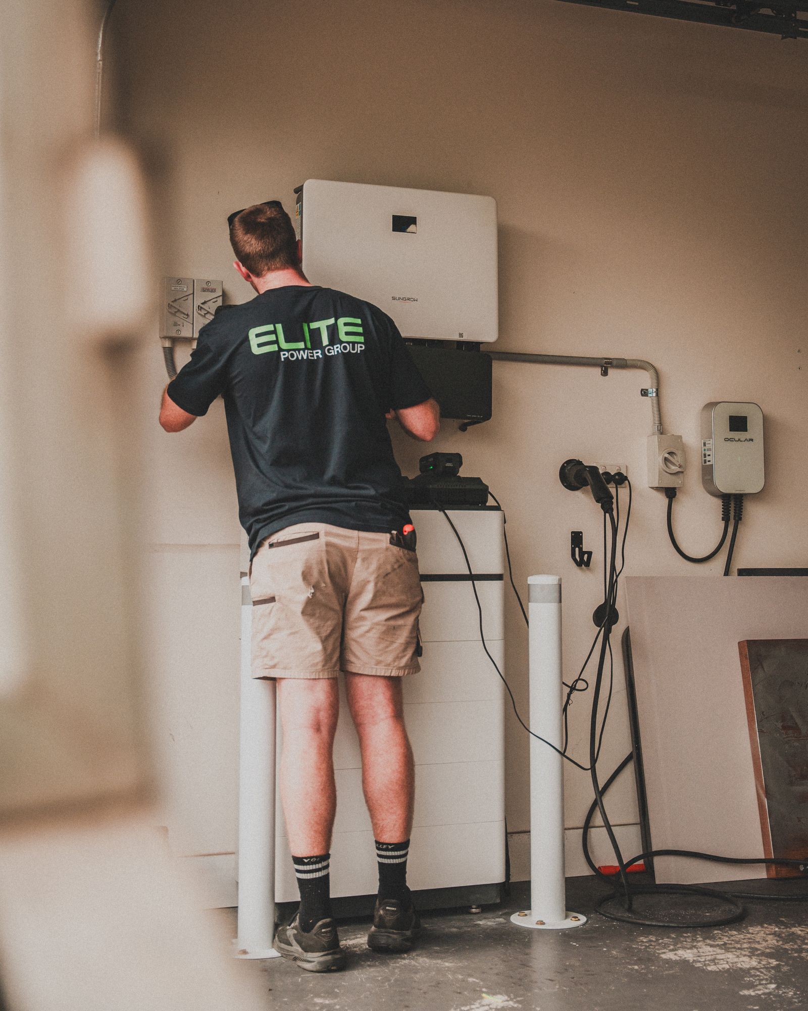 Technician installing wall-mounted charging equipment and cables