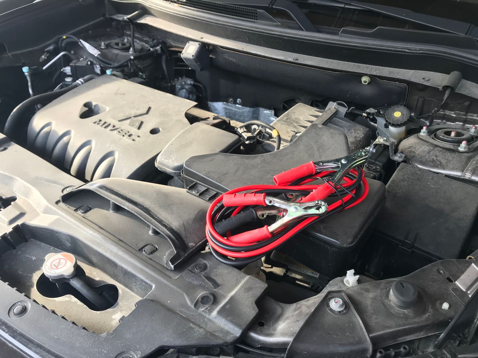 Jumper leads and battery in a vehicle engine bay