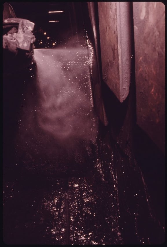 Dust-suppression spray in a mining environment illustrates combined dust and moisture exposure.