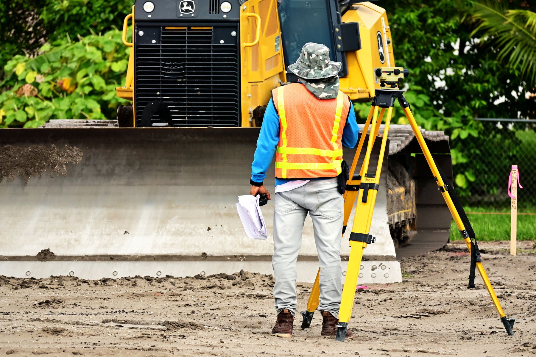 Survey worker using a tripod-mounted surveying instrument