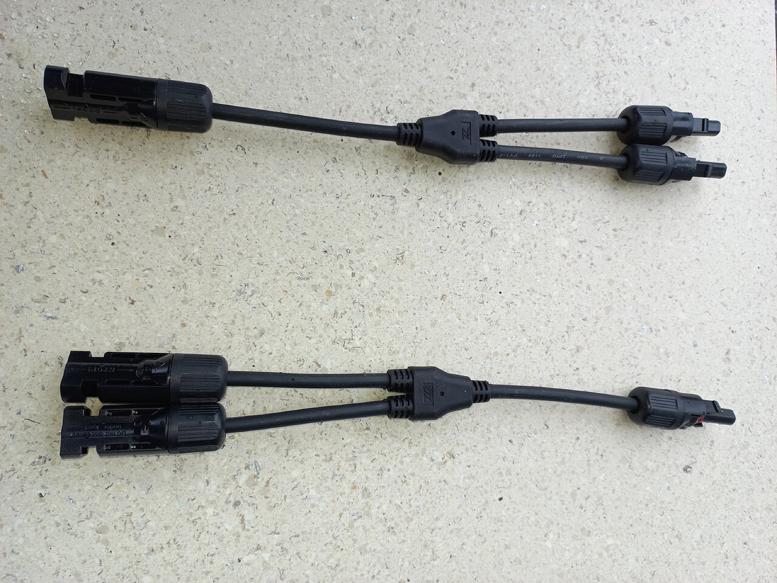 Two third-party MC4 solar cable branches with molded junctions on a light surface