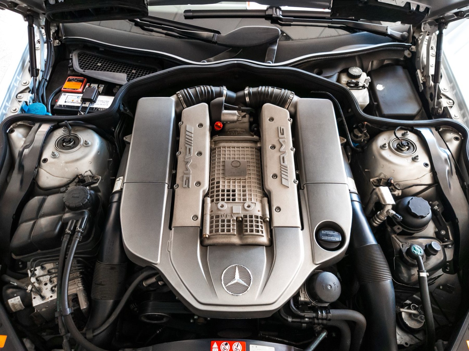 Vehicle engine cover and surrounding engine-bay structure