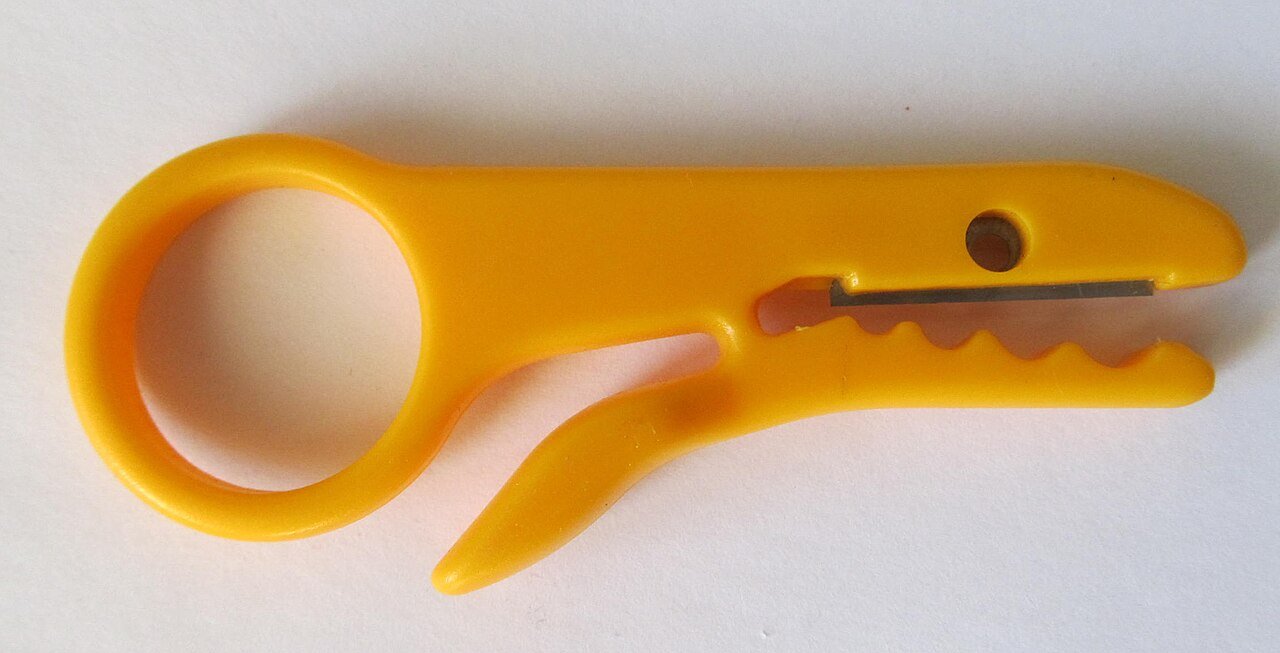 A hand stripping tool illustrates cable preparation; production tooling must match the cable and termination.