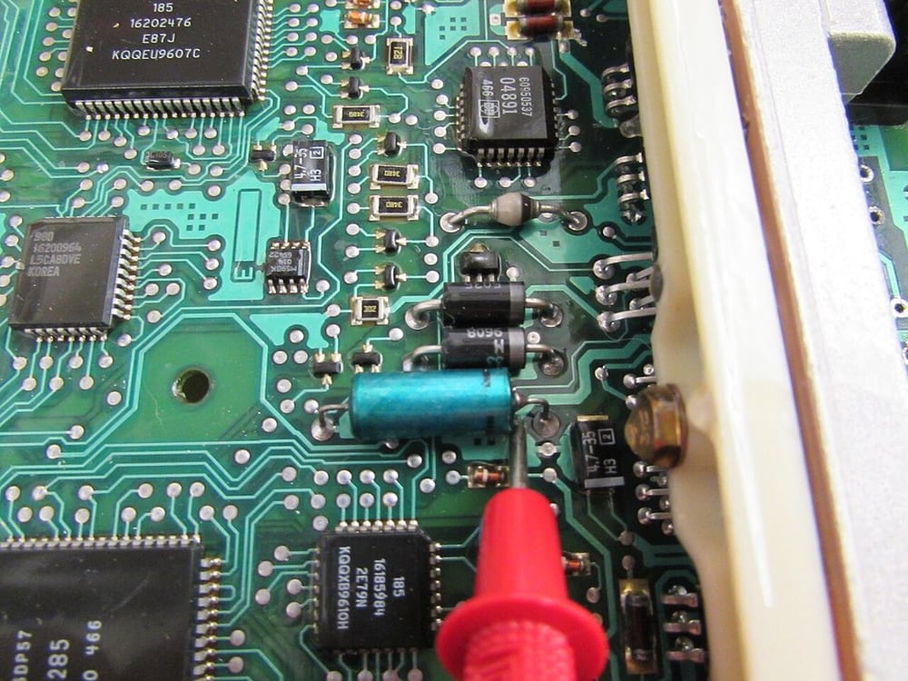 A vehicle ECU board under inspection provides automotive-electronics context.