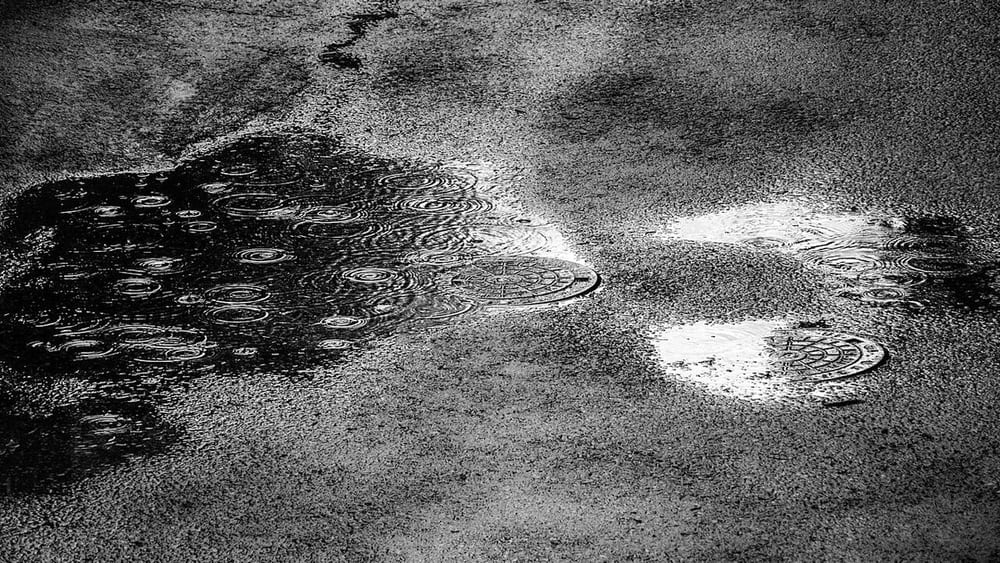 Rain striking standing water illustrates environmental exposure, not a product ingress test.