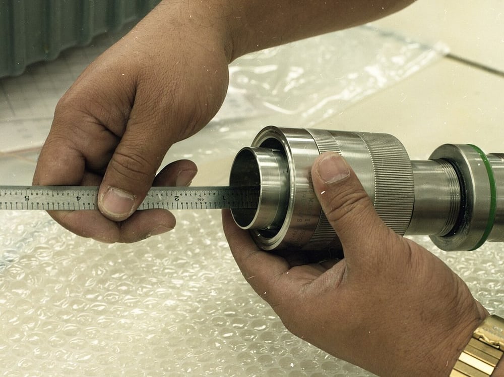 A technician measuring a cable-end component illustrates explicit dimensional datums.