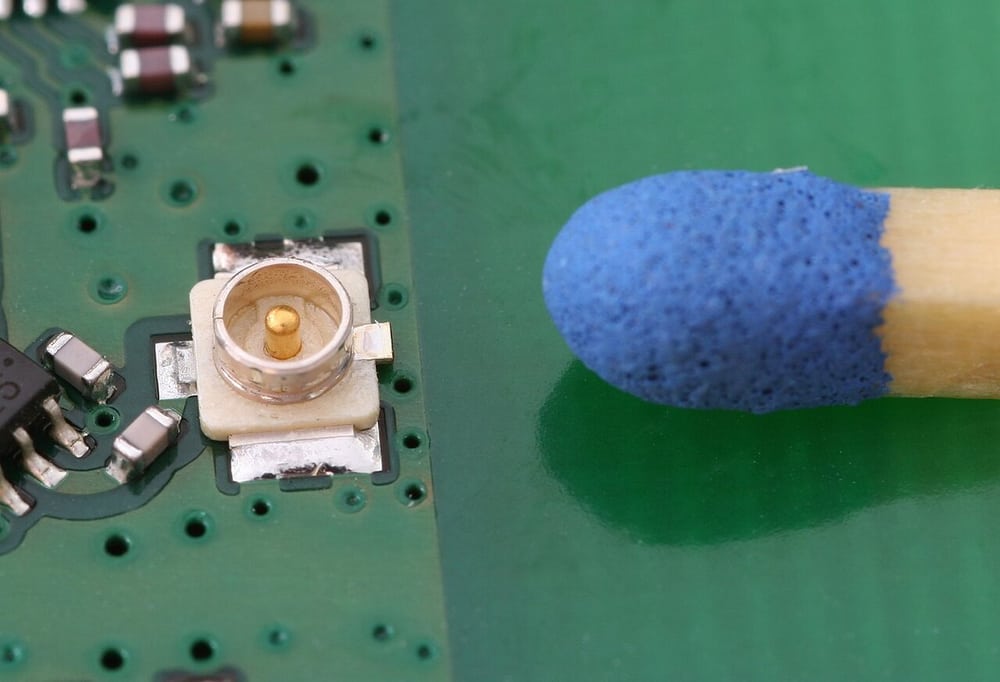 Miniature board connector beside a match head shows the scale of careful handling.