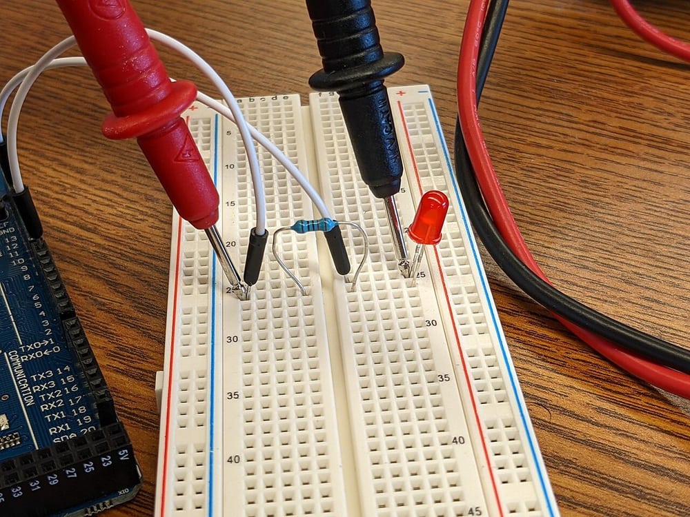 Meter probes on a circuit illustrate electrical connection checks, not production acceptance results.