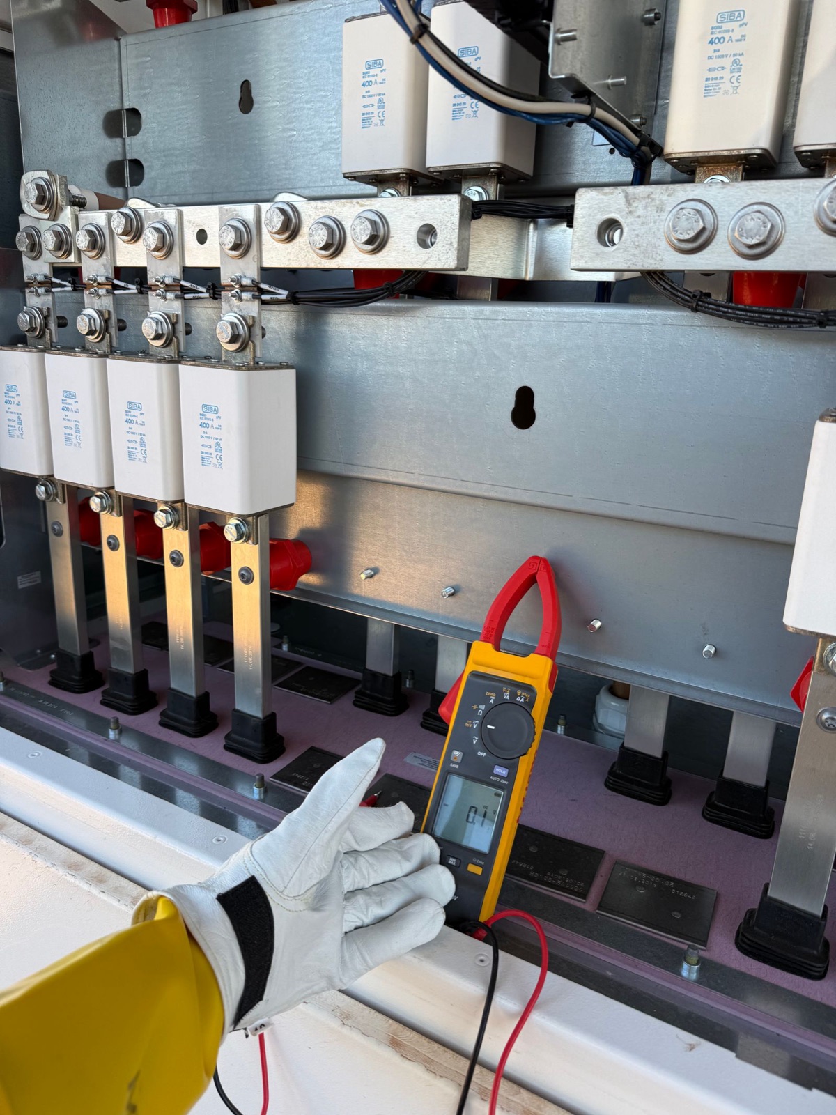 Technician measuring an outdoor electrical cabinet with a multimeter