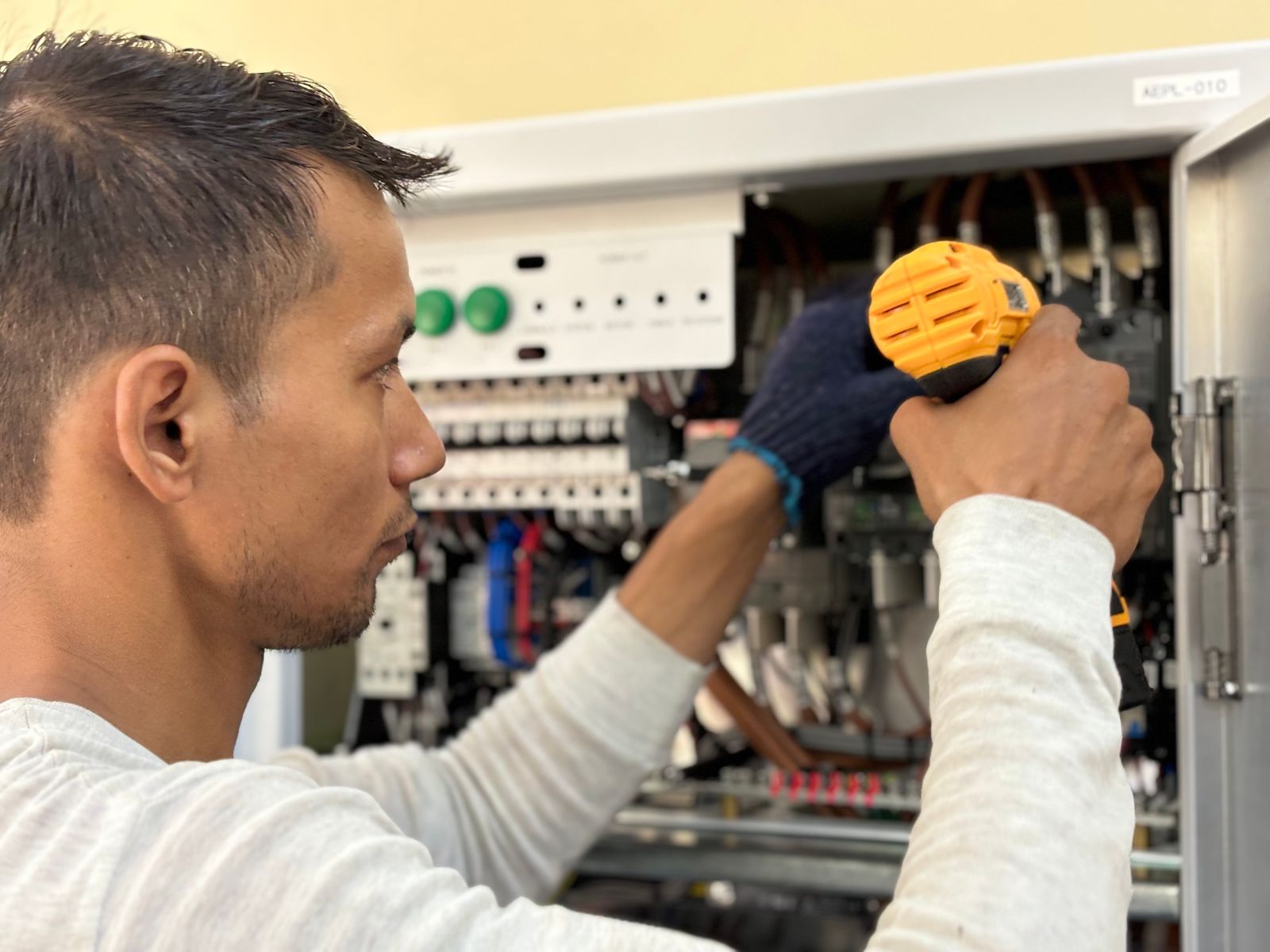 Technician using a handheld meter at a control cabinet