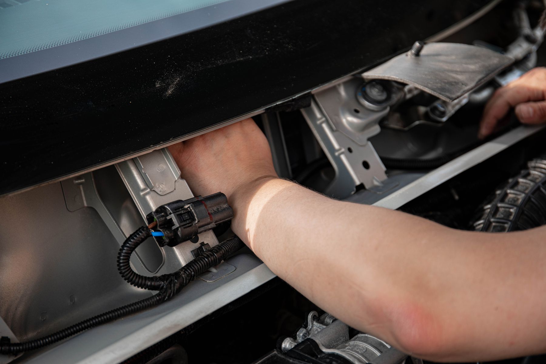 Person accessing a trailer socket at the rear of a vehicle