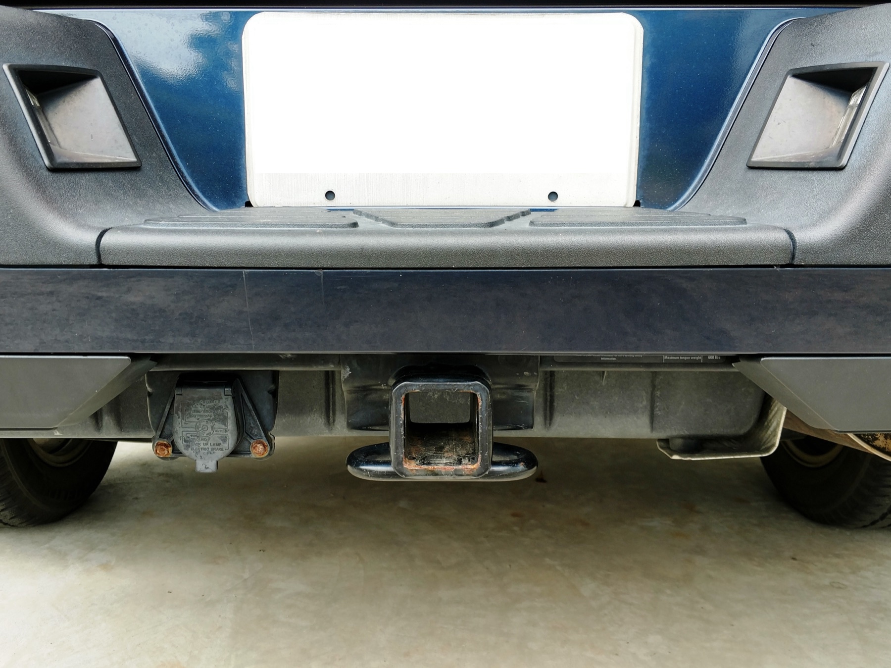 Towing hardware beneath a vehicle rear bumper