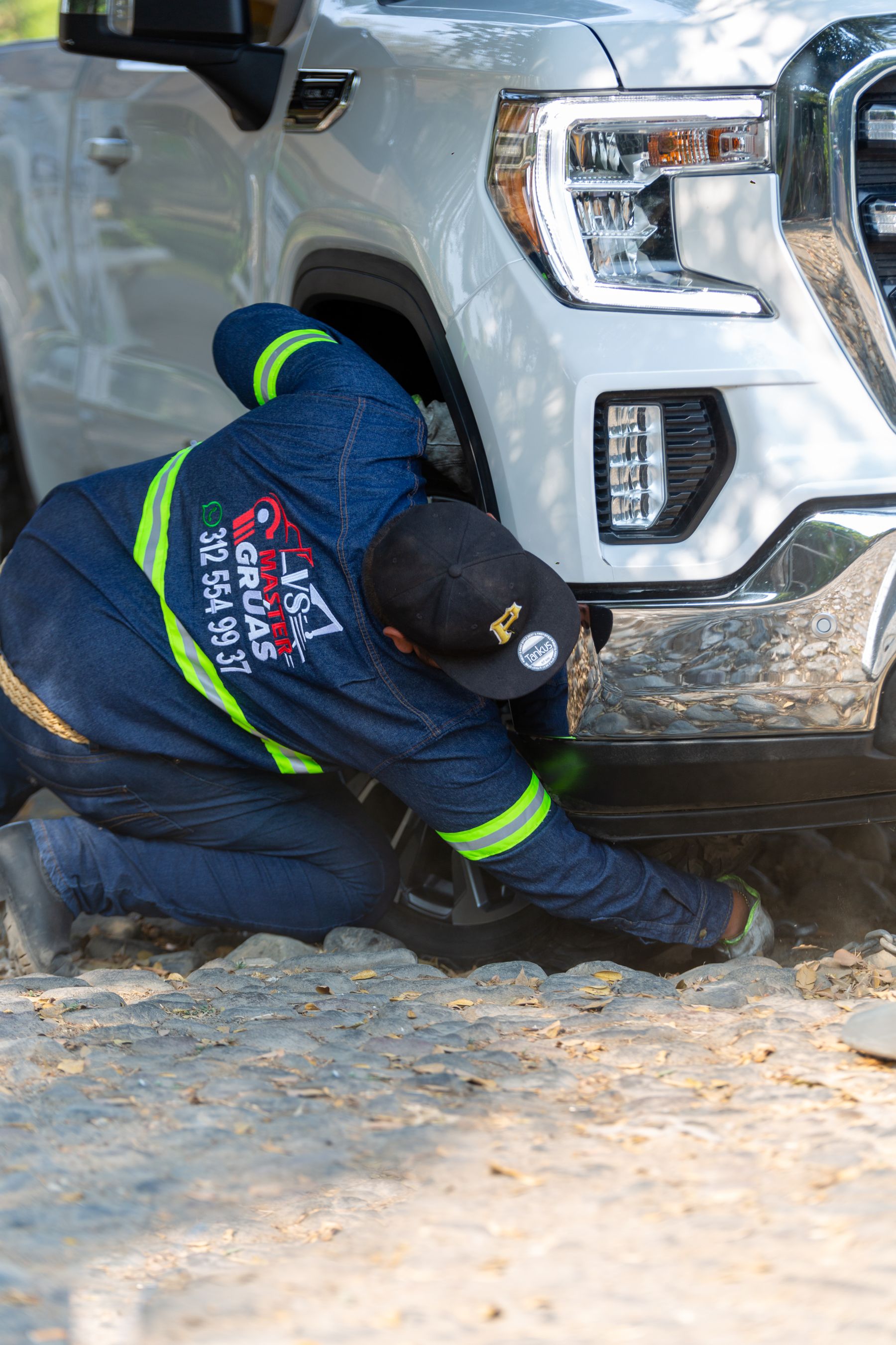Worker servicing beside a large vehicle front wheel